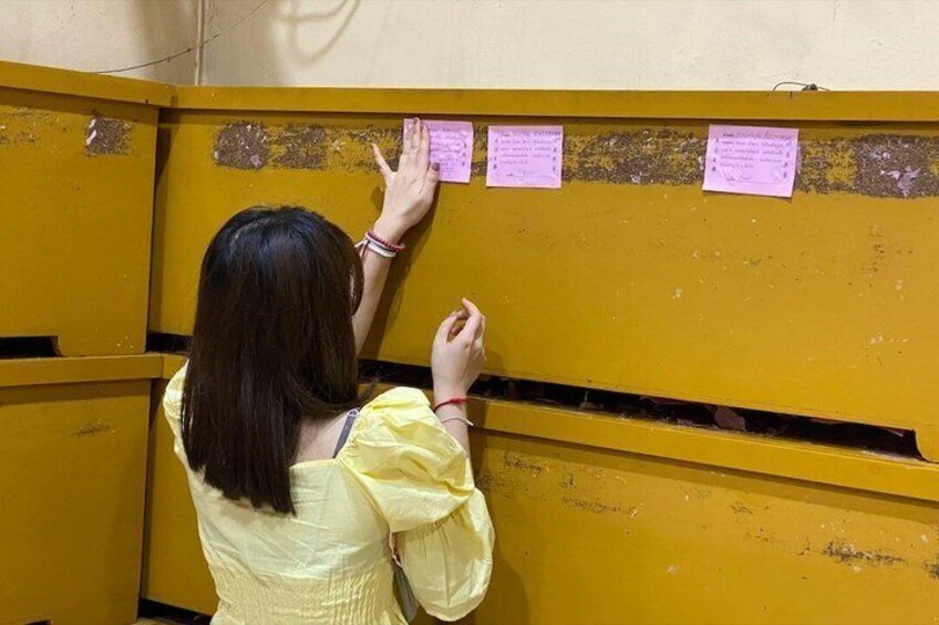A person standing in front of a yellow partition with notes attached to it. 4