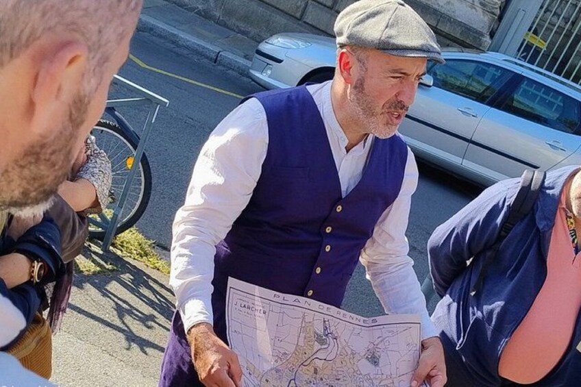 A person holding a map, standing on a sidewalk with a bicycle and a car in the background. 2