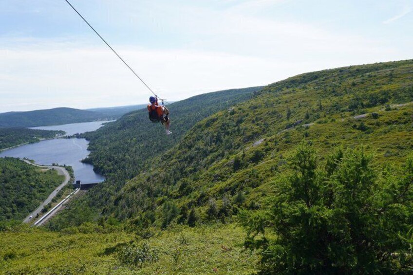A person bungee jumping off a cliff with a river and forested hills in the background. 3