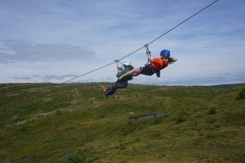 A person zip-lining over a grassy landscape. 2