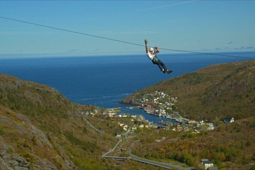A person bungee jumping from a high wire over a coastal town. 1