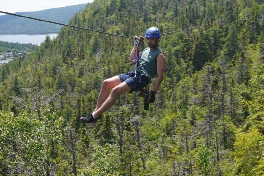 A person zip-lining through a forested area with a lake in the background. 4