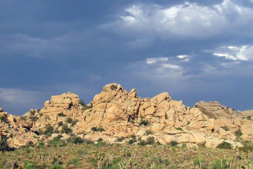 A rocky mountain range with sparse vegetation under a cloudy sky. 1