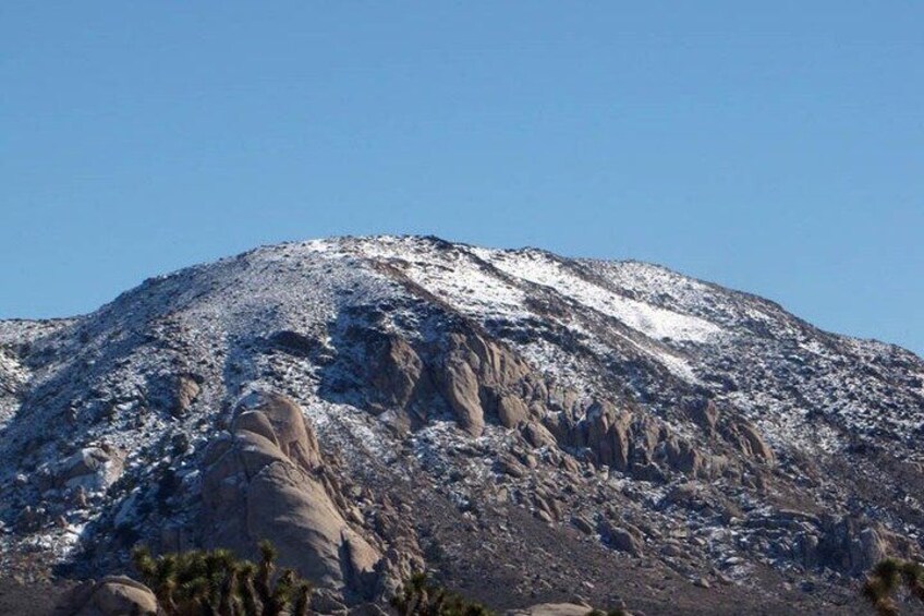A snow-capped mountain with rocky terrain and sparse vegetation. 2