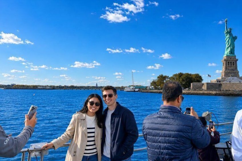 A group of people on a boat with the Statue of Liberty in the background. 3