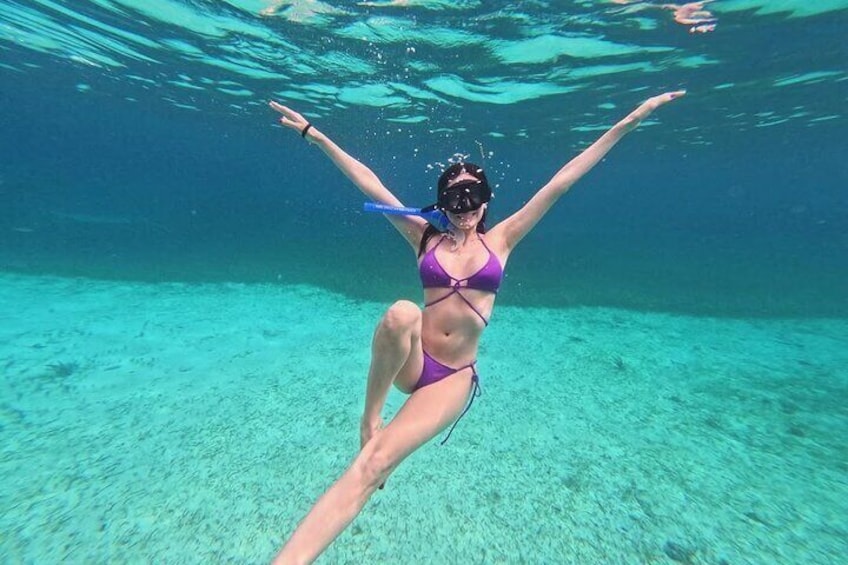 A person swimming underwater in clear blue water. 5