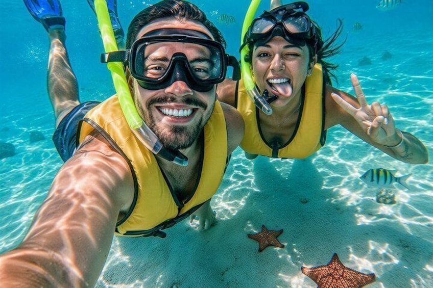 Two people snorkeling underwater with starfish on the ocean floor. 1