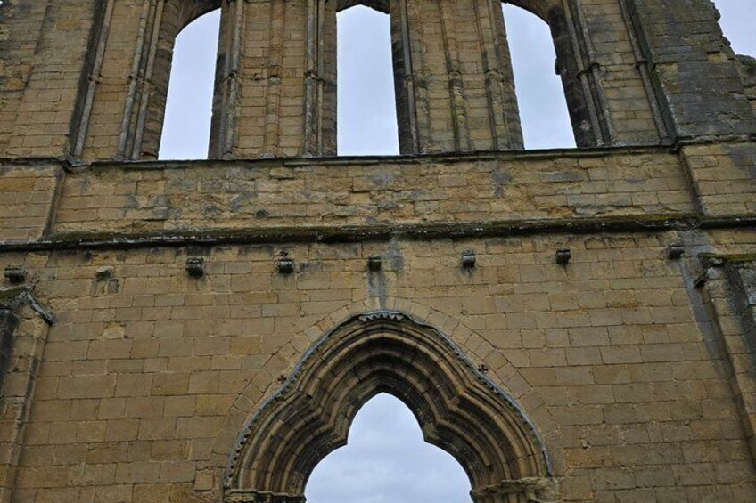 A historic stone structure with arched windows and a central archway. 3