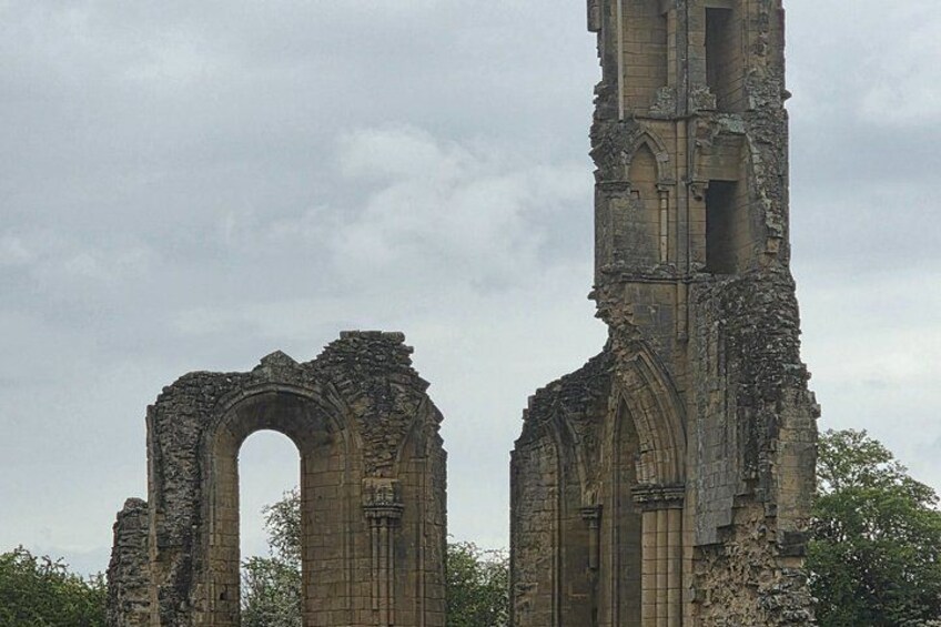 Ancient ruins with arched structures and a tall tower. 2