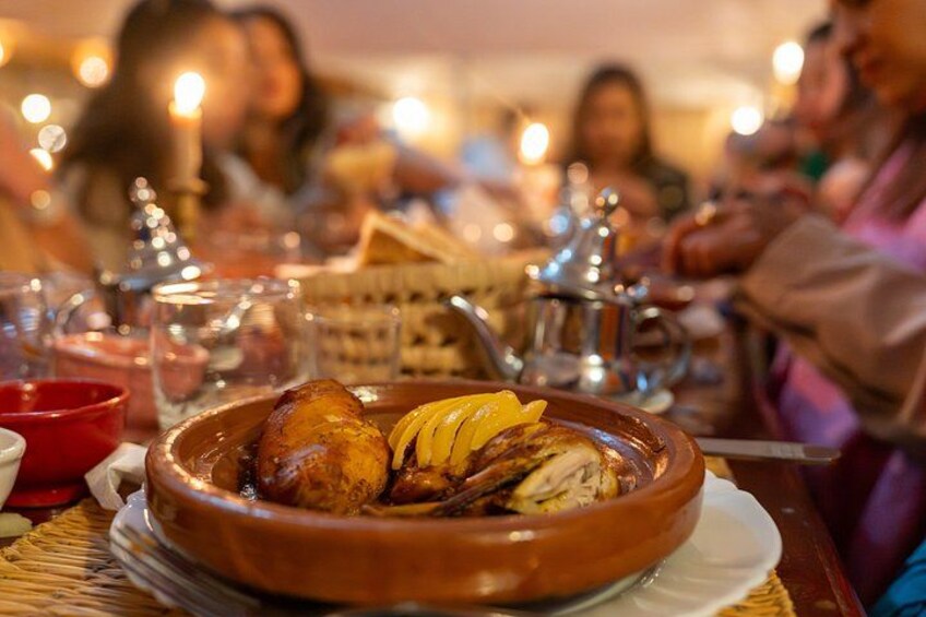 A clay pot with roasted meat and vegetables, a teapot, and a glass of red wine on a table in a restaurant. 4