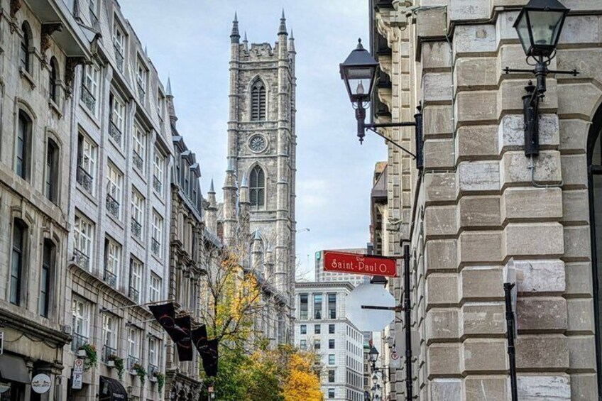 A historic building with a clock tower, a street sign for 'Saint-Paul,' and autumn foliage. 5