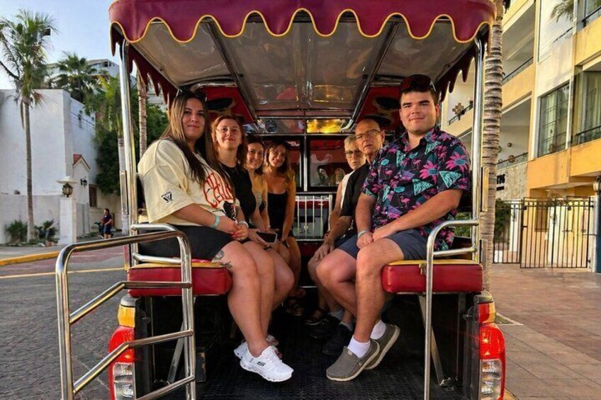 A group of people seated in a covered vehicle with a red and yellow exterior. 5