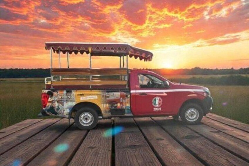 A red truck with a canopy on a wooden dock at sunset. 2