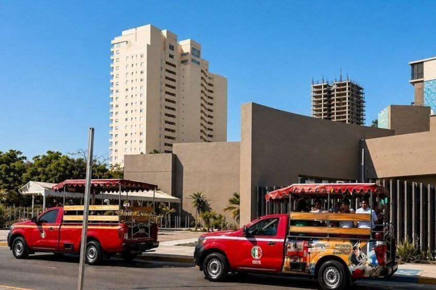 Two red trucks with colorful decorations parked on a city street. 4