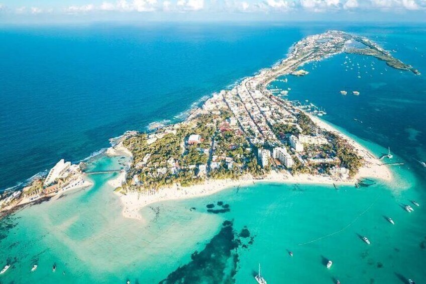 An aerial view of a coastal town with a beach, clear turquoise waters, and boats. 1