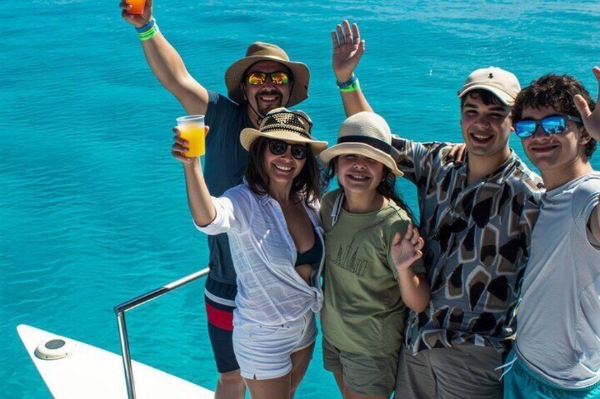 A group of people on a boat with a clear blue sea in the background. 2