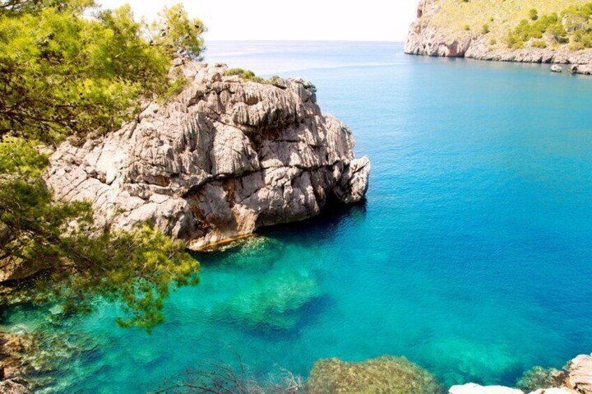 A rocky coastline with clear turquoise waters and green vegetation. 3