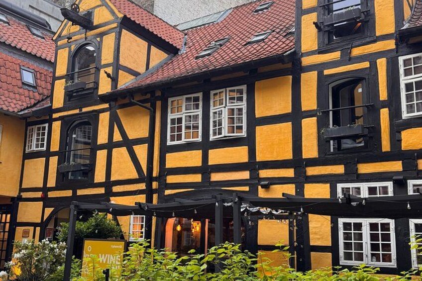 A traditional half-timbered building with a red-tiled roof and a signboard in front. 1