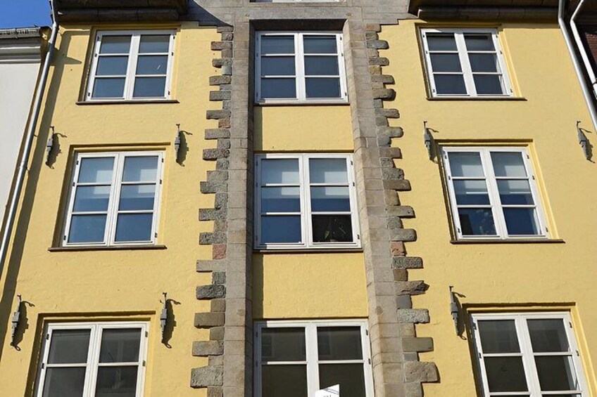 A yellow building with multiple windows and stone detailing. 3