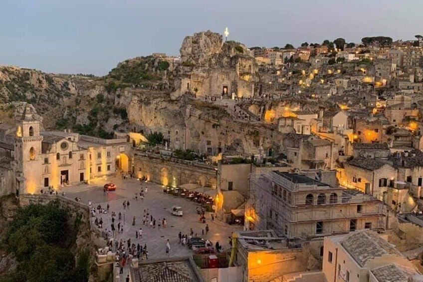 A historic town with a prominent church, a plaza, and buildings nestled in a rocky hillside. 1