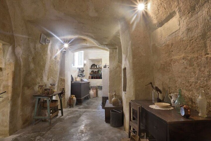 A rustic stone interior with a narrow passageway leading to a kitchen area. 5