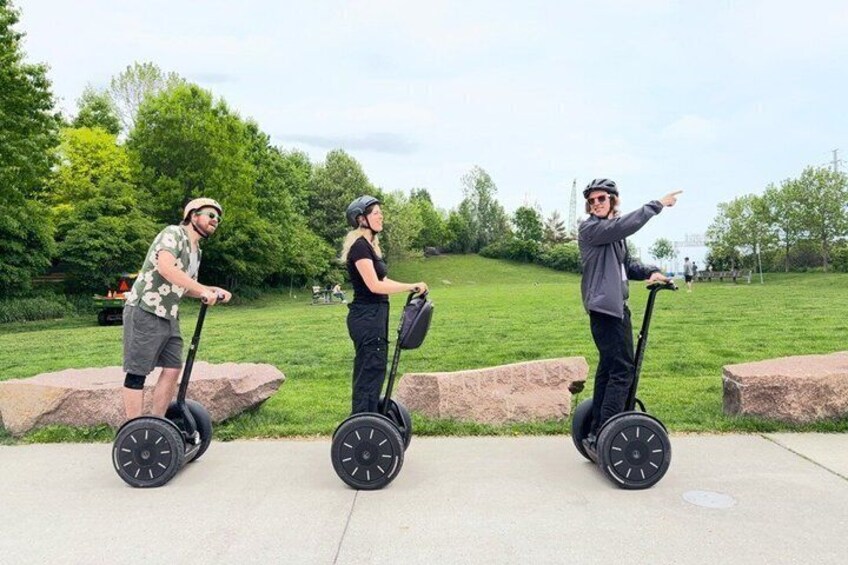 Three people on Segways in a park with grass and rocks. 2