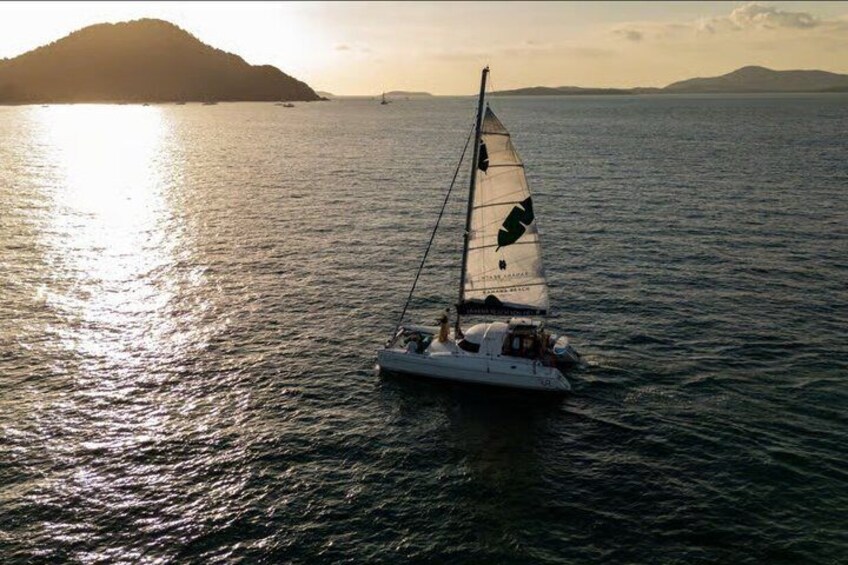 A sailboat on calm waters with a distant landmass and a clear sky. 5