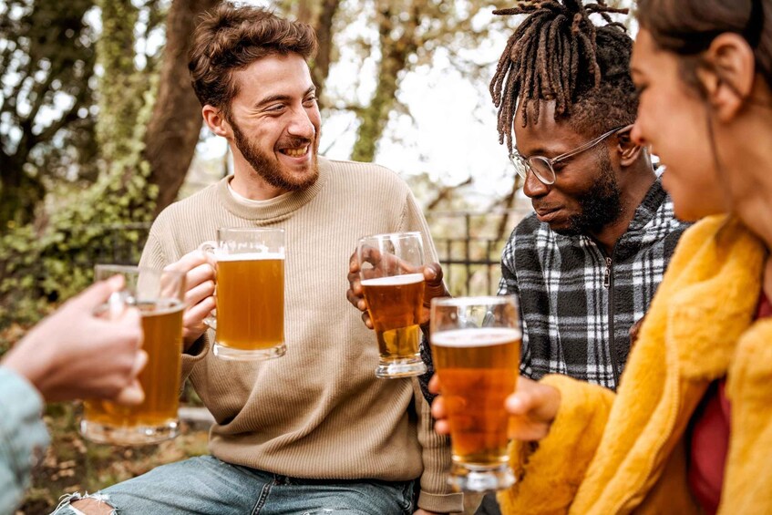 People toasting with beer glasses outdoors. 1