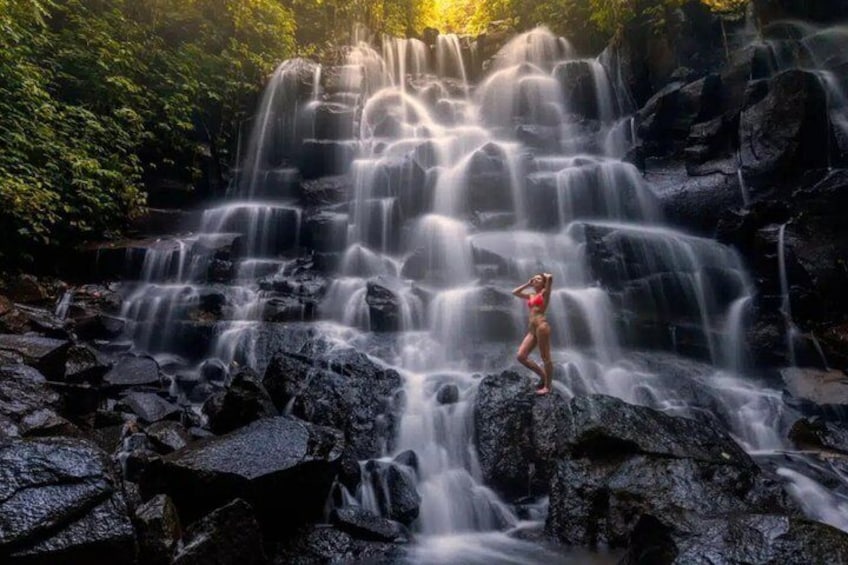 A waterfall with a person standing on rocks. 3