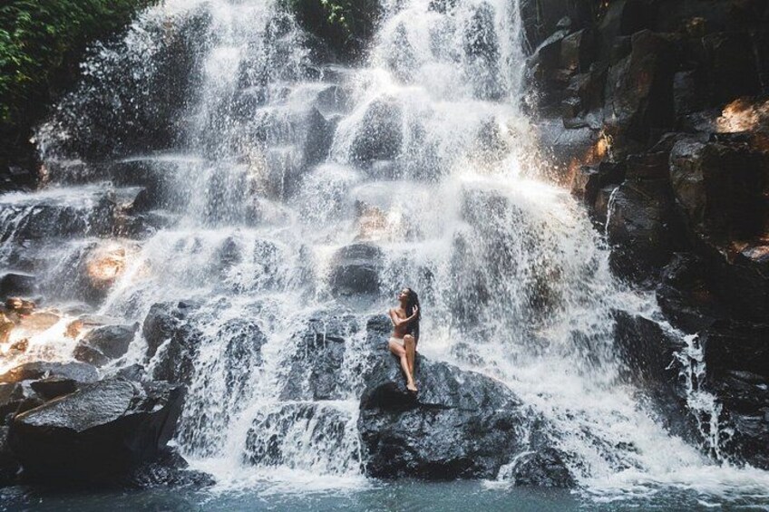 Ein Wasserfall mit einer Person, die auf Felsen steht. 5