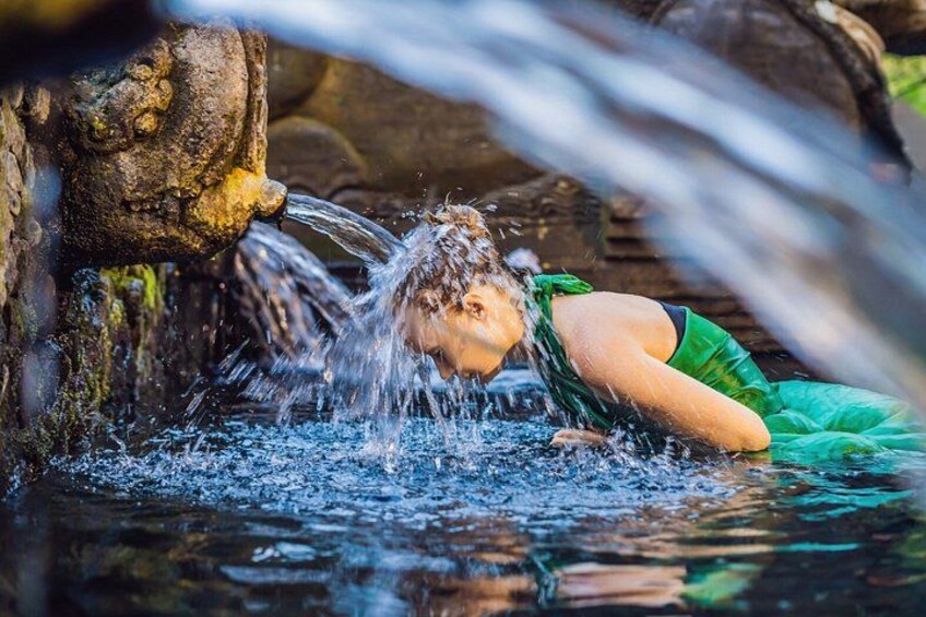 A person in a green dress near a water stream with a rocky background. 3