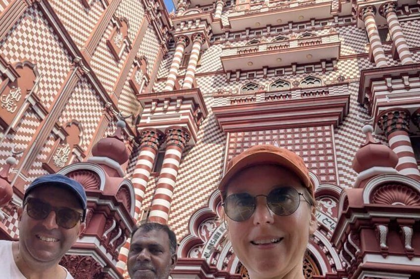 A person standing in front of a building with intricate red and white patterned architecture. 5