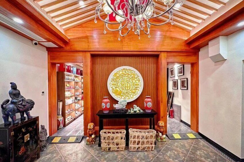 A traditional interior with a wooden ceiling, a chandelier, a decorative wall piece, and a statue. 4