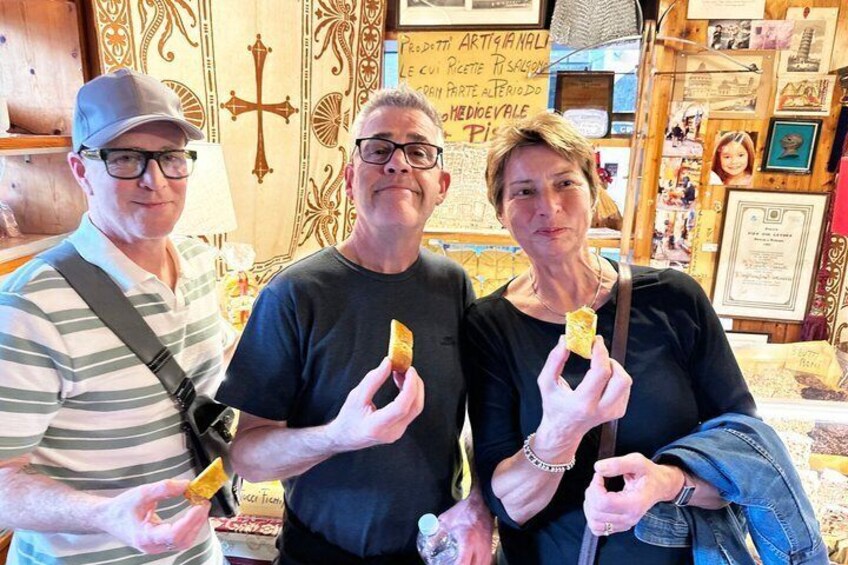 Three people holding bread in a shop with wooden decor and a cross symbol. 3