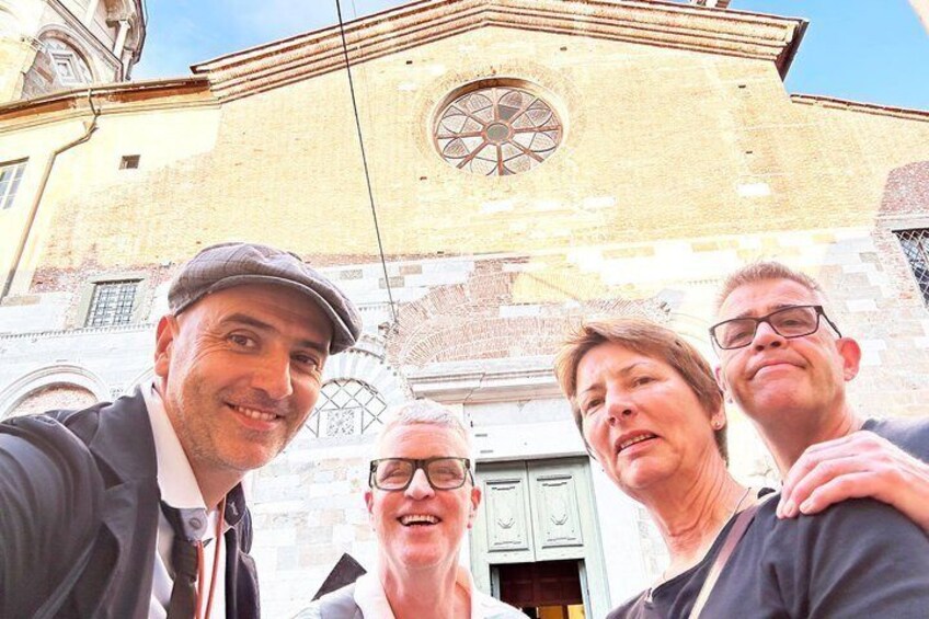 A group of people in front of a building with a large circular window and a brick facade. 2