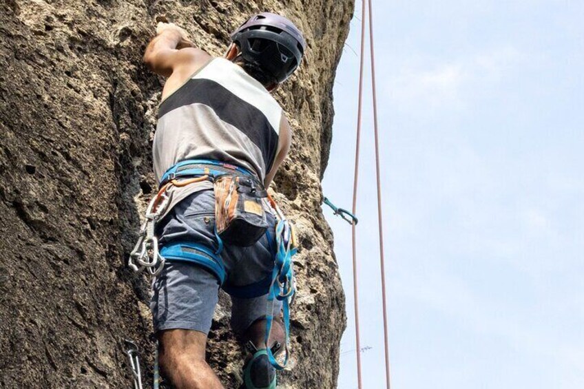 A person climbing a rock face with climbing gear. 1