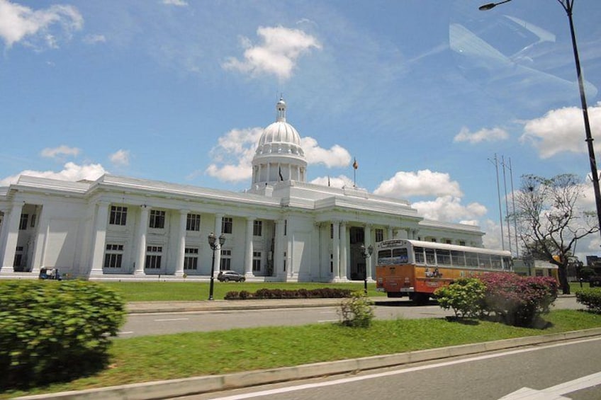 A large white building with a dome, a bus in front, and a clear blue sky. 1