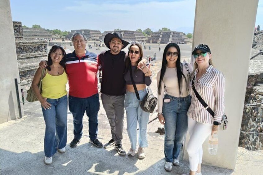 A group of people posing in front of ancient ruins with stepped structures and a clear sky. 4