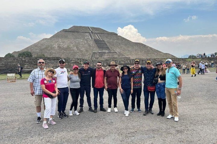 A group of people standing in front of a large pyramid-like structure. 3