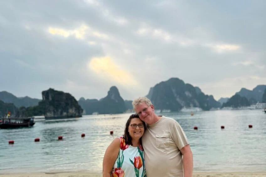 A couple standing on a beach with a backdrop of limestone karsts and calm waters. 4