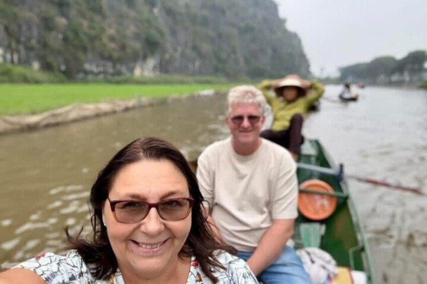 A river with boats, a person in the foreground, and a person in the background wearing a hat. 5