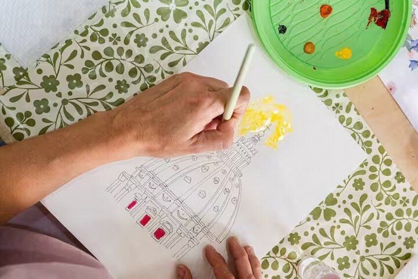 A hand coloring a drawing of a building with a paintbrush. 1