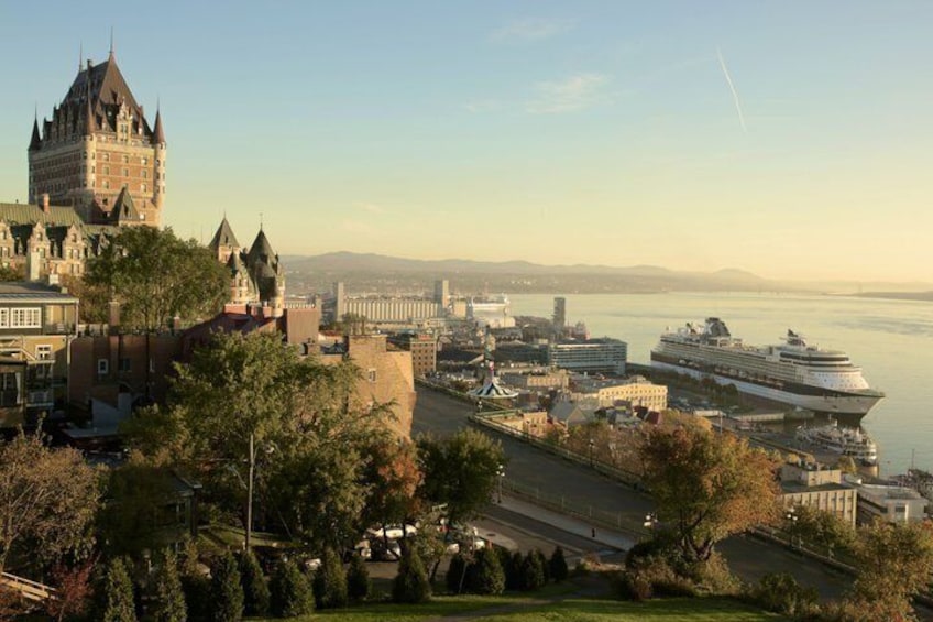 A cruise ship docked at a port with a historic castle in the foreground. 5