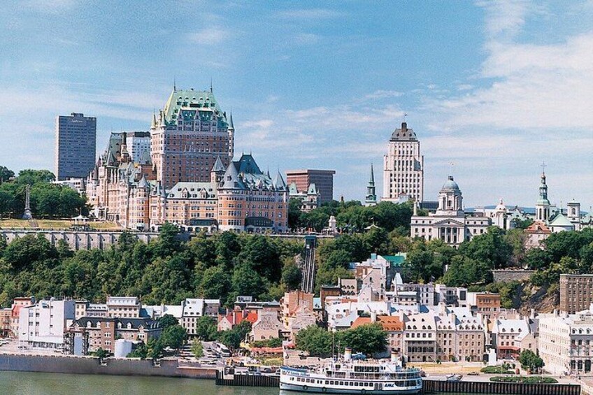 A cityscape with historic buildings, a river, and a prominent castle-like structure. 1