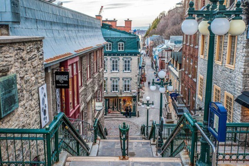 A historic street with stone buildings, a staircase, and vintage street lamps. 3