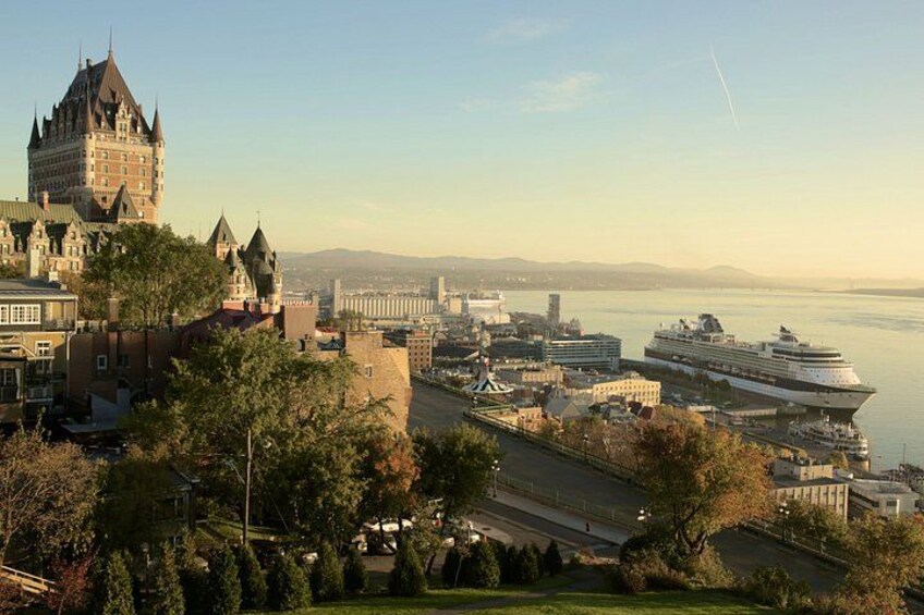 A cruise ship docked at a port with a castle-like building in the foreground. 5