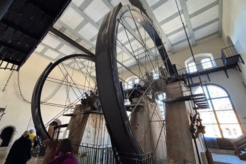 A large mechanical wheel structure with scaffolding and a person in a pink jacket. 1