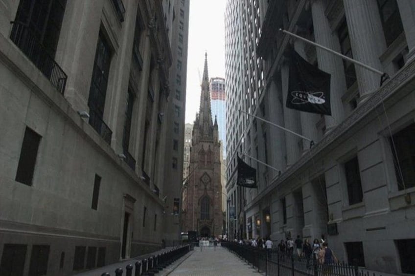 A street with tall buildings, a church spire, and a flag. 1