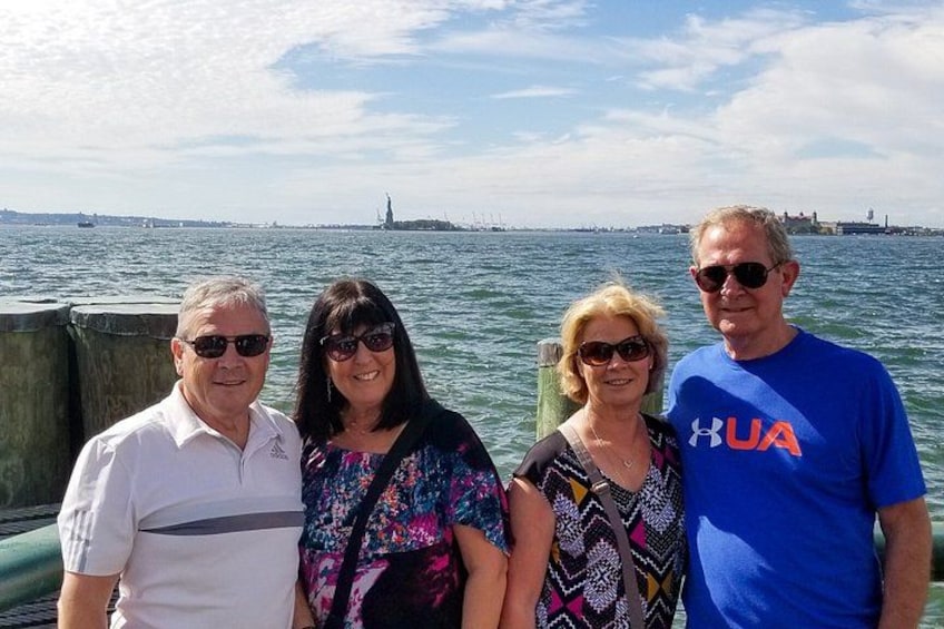 A group of people standing by a waterfront with a statue in the background. 4