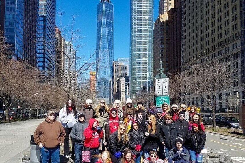 A group of people posing in an urban setting with tall buildings and a clear sky. 2